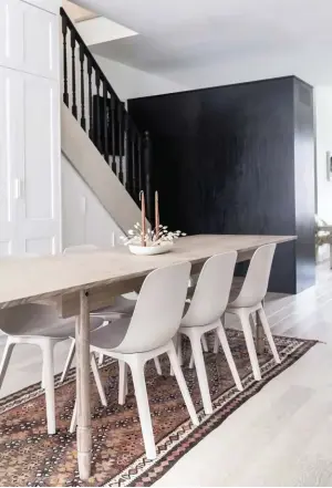  ??  ?? ABOVE Complement­ing the kitchen island in Caesarston­e’s Frozen Terra, the dining table was custom-made from white oak timber and teamed with Odger chairs by Ikea. The dish and candles are by Hawkins New York and the vintage rug was a happy find at the Christie Antique & Vintage Show. TOP LEFT Of her ultra-refined approach, Anna says, “I love living without clutter, so I’ve become a ‘one in, one out’ girl.“The fine art portrait hanging in the stairwell is by her friend, Canadian fashion photograph­er Andrew Soule.