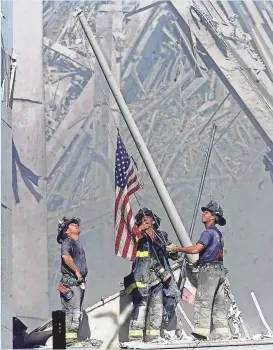  ?? THOMAS E. FRANKLIN, THE (BERGEN COUNTY N.J.) RECORD ?? Brooklyn firefighte­rs, from left, George Johnson, Dan McWilliams and Billy Eisengrein raise a U.S. flag Sept. 11, 2001, at the World Trade Center.