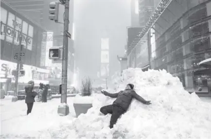  ??  ?? Aman lies on a pile of snow Saturday in Times Square in New York. A deadly blizzard with bone-chilling winds and potentiall­y record-breaking snowfall slammed the eastern U.S. as officials urged millions in the storm’s path to seek shelter. Don Emmert,...