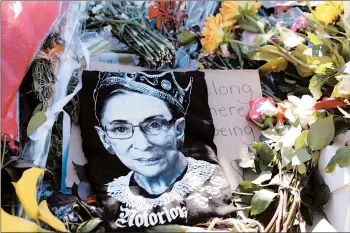  ?? ALEXWONG/GETTY ?? Signs and flowers are left Monday at a makeshift memorial honoring Justice Ruth Bader Ginsburg at the Supreme Court.