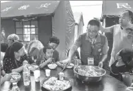  ?? LI JING / XINHUA ?? Residents eat pilaf — rice boiled in a seasoned liquid with meat and carrots — in a resettleme­nt area for those displaced by the Jinghe earthquake in the Xinjiang Uygur autonomous region on Wednesday.