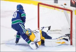  ?? The Canadian Press ?? Vancouver Canucks forward Elias Pettersson dekes around Nashville Predators goalie Pekka Rinne to score on a second-period penalty shot.