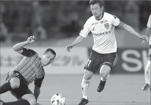  ?? AFP ?? Yokohama FC’s Kazuyoshi Miura is tackled by Kawasaki Frontale’s Leandro Damiao during a J-League match on Sept 23 last year. Miura, aka King Kazu, is preparing to kick off his 36th season as a profession­al soccer player at the age of 54.