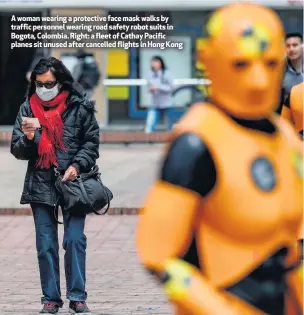  ??  ?? A woman wearing a protective face mask walks by traffic personnel wearing road safety robot suits in Bogota, Colombia. Right: a fleet of Cathay Pacific planes sit unused after cancelled flights in Hong Kong