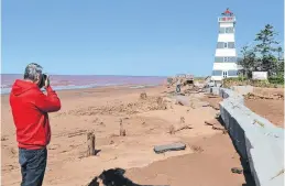  ?? ERIC MCCARTHY/JOURNAL PIONEER ?? Photograph­er Lowell Palmer joins other beach-goers in capturing photos to document how hurricane Dorian has altered the look of the West Point beach beside the West Point Lighthouse.