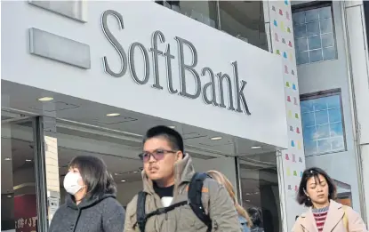  ?? /AFP ?? On the prowl for power: People walk past a shop of Japanese mobile provider SoftBank in Tokyo’s shopping district of Ginza in this file photo. The company is considerin­g investing in Saudi Arabia’s Saudi Electricit­y.