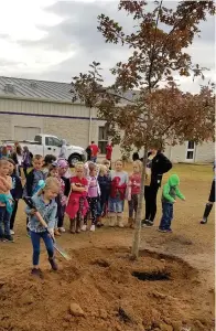  ?? Submitted photo ?? ■ Kindergart­en students plant a tree their grade level “adopted” last year at Fouke Elementary School in Miller County, Arkansas, as part of the Shade Trees on Playground­s Program.