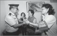  ?? PROVIDED TO CHINA DAILY ?? A police officer at the Taoranting police station in Beijing is greeted by social workers at a community in the precinct last month.