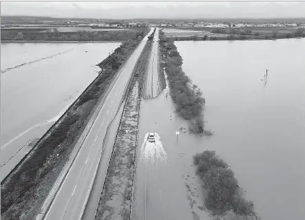  ?? Photograph­s by Shmuel Thaler Santa Cruz Sentinel ?? A CALTRANS VEHICLE heads north through floodwater­s that closed State Highway 1 at the Santa Cruz County line on Sunday.