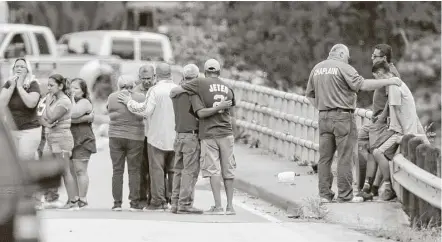  ?? Elizabeth Conley / Houston Chronicle ?? Relatives console one another as a van is pulled out of Greens Bayou with the bodies of six family members Wednesday.