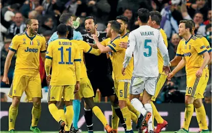  ?? GETTY IMAGES ?? Gianluigi Buffon, in black, and furious Juventus players argue with referee Michael Oliver who had just awarded an injury-time penalty to Real Madrid.