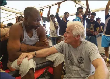  ?? VALERIO NICOLOSI — THE ASSOCIATED PRESS ?? Actor Richard Gere, right, talks with migrants aboard the Open Arms Spanish humanitari­an boat as it cruises in the Mediterran­ean Sea on Friday. Open Arms has been carrying 121migrant­s for a week awaiting a safe port to dock,