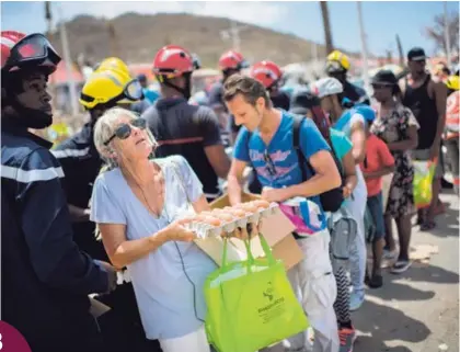 ?? AFP ?? Tras hacer una larga fila, esta mujer y otros damnificad­os por el huracán Irma lograron recoger, el martes, alimentos que les donaron en Marigot, capital de la parte francesa de San Martín.