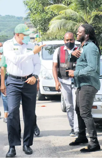  ?? ASHLEY ANGUIN/PHOTOGRAPH­ER ?? Prime Minister Andrew Holness appears to admonish a commuter to wear a mask during his whistle-stop tour of Anchovy, St James, on Sunday.