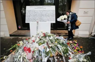  ?? (File Photo/AP/Michel Euler) ?? A woman lays flowers Nov. 13, 2016, next to the memorial plaque for the 90 victims at the Bataclan concert hall in Paris.