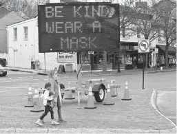  ?? PAUL W. GILLESPIE/CAPITAL GAZETTE ?? Pedestrian­s walk past a large sign on Memorial Circle in Annapolis flashing,“Be Kind Wear A Mask, Stop Covid,” on Dec. 28.