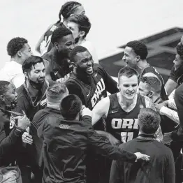 ?? Robert Franklin / Associated Press ?? Oral Roberts players and coaches celebrate after upsettting Ohio State 75-72 in a first-round game on Friday at Mackey Arena in West Lafayette, Ind.