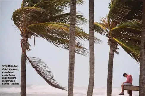  ??  ?? SEORANG lelaki duduk di menara penyelamat pantai ketika angin kencang di Hollywood, Florida. - Reuters