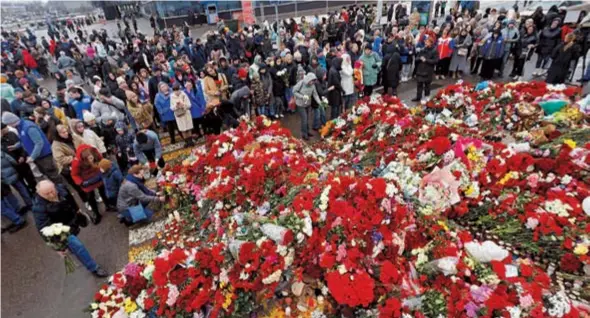  ?? ?? People gather at a makeshift memorial to the victims of a shooting attack set up outside the Crocus City Hall concert venue in the Moscow region of Russia yesterday. — Reuters