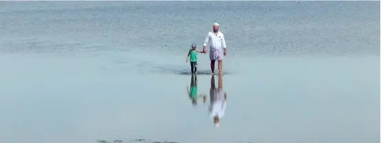  ?? Pic by Hiran Priyankara ?? Relief to residents: As Puttalam received rain after a prolonged drought, a father and son enjoy a walk on Puttalam Wewa that filled up a little yesterday.