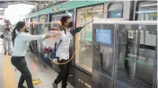  ?? — PTI ?? A Noida Metro official warns the worker spraying disinfecta­nt on a metro about the high tension wires running over the metro line.