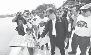  ??  ?? TERTARIK: Abang Johari melihat gambar pembanguna­n sekitar kawasan Kampung Masjid pada pelancaran Program ‘World Clean Up Day’ di kampung itu, semalam.