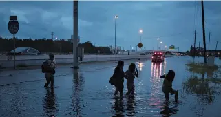  ??  ?? MEMBERS of the Duong family walk through flood waters from tropical storm Harvey on the feeder road of Interstate 45 in Houston, Texas, Aug. 27.