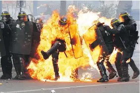  ?? — GETTY IMAGES ?? French anti-riot police officers are engulfed in flames as they face protesters in Paris on Monday.