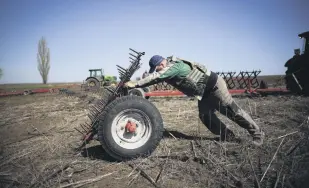  ?? ?? A Ukrainian farmer, wearing body armor, works in the topsoil in a field in the Zaporizhzh­ia region, Ukraine, April 26, 2022.