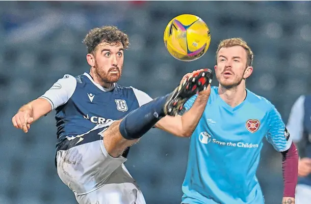 ??  ?? FIGHTING SPIRIT: Dundee’s Shaun Byrne clears the ball ahead of Andy Halliday of Hearts during the Dens men’s 3-1 win over the league leaders.