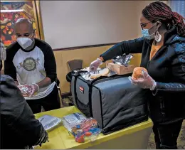  ??  ?? Genea Moore, right, and John Perkins, second from left, prepare meals for residents at an emergency shelter in Calumet City on Nov. 25.