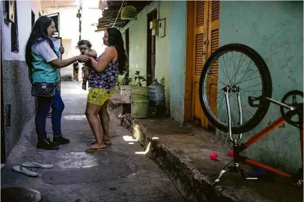  ??  ?? A agente de saúde Janaína Alves, à esq., visita a casa de uma das crianças cuja vacinação ela acompanha