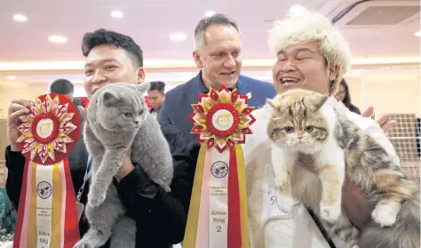  ??  ?? Vice-chairman of the World Cat Federation Albert Kurkowski, centre, presents titles to cats of Tawin Prai from Thailand, right, and Nguyen Xuan Son from Vietnam.