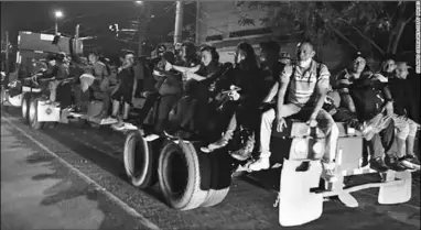  ??  ?? Hondurans sit on the flat bed of a truck as they leave for the US. (Photo:CNN)