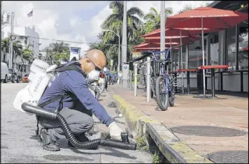  ?? AP ?? Miami-Dade mosquito control inspector Yasser “Jazz” Compagines sprays a chemical mist into a storm drain on Tuesday in Miami Beach. Gov. Rick Scott said the Florida Department of Health is allocating another $5 million in funding to fight Zika.