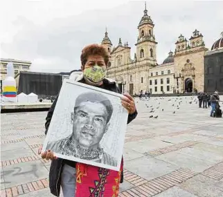  ?? EFE ?? Una mujer muestra, durante un plantón ayer en Bogotá, la imagen de un familiar desapareci­do.