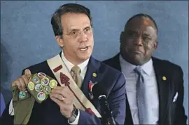  ?? Patrick Semansky Associated Press ?? JEFF DION, chief executive of the Zero Abuse Project, shows old merit badges during a news conference this week on the Boy Scouts of America abuse scandal.