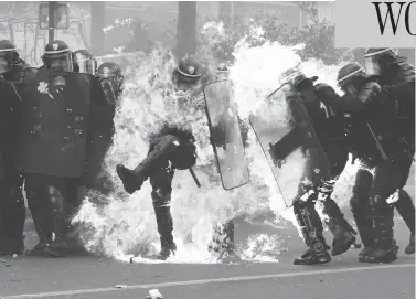  ?? ZAKARIA ABDELKAFI/AFP/GETTY IMAGES ?? French anti-riot police officers are engulfed in flames as they face protesters during a march for the annual May Day workers’ rally in Paris Monday. The traditiona­l rallies gained extra resonance ahead of Sunday’s runoff vote.