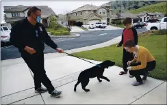  ??  ?? Dog trainer Joby Hurst introduces Molly and Matthew Ouimet, 18 and 10, to their Labrador companion dog Winnie recently at the Ouimets’ Antioch home.