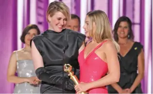  ?? SONJA FLEMMING/CBS VIA AP ?? Director and co-writer Greta Gerwig, left, and actor Margot Robbie accept the award for best cinematic and box office achievemen­t for the film “Barbie” on Sunday during the Golden Globe Awards in Beverly Hills, Calif.