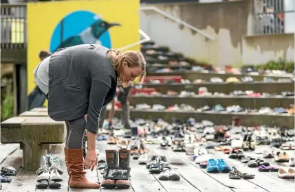  ?? PHOTO: SIMON OCONNOR/STUFF ?? Rochelle Herlihy places a photograph of her with her brother Michael on his Red Band gumboots at a remembranc­e event in New Plymouth on Wednesday to those who committed suicide between June 2015 and June 2016.