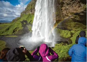  ?? Foto: Daniel Naupold, dpa ?? Touristen besichtige­n den Wasserfall „Seljalands­foss“in Island.