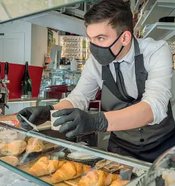  ??  ?? Al bancone Un barista con guanti e mascherina serve un caffè da asporto