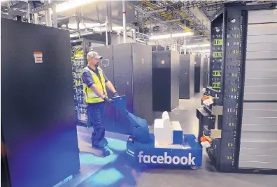  ?? JIM THOMPSON/JOURNAL ?? A logistics specialist uses a tug to move a server rack in one of the data halls at the newly opened Facebook data center in Los Lunas.