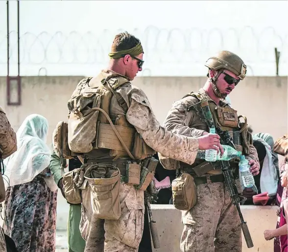  ??  ?? Los marines dan agua a una niña afgana ayer, en el aeropuerto internacio­nal de Kabul