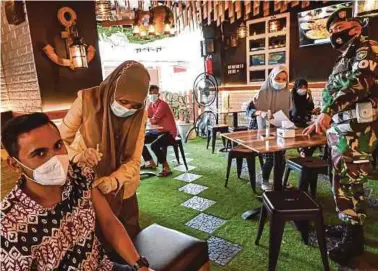  ?? AFP PIC ?? A man receiving a dose of the Sinovac vaccine at a cafe in Banda
Aceh on Wednesday.