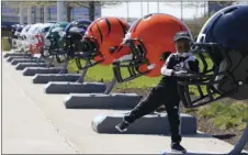  ?? AP PHOTO/TONY DEJAK ?? Joseph Toliver, 4, plays on one of the 32 NFL team helmets on display, April 13, in downtown Cleveland.