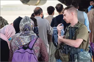  ?? Senior Airman Taylor Crul / Associated Press ?? In this image provided by the U.S. Air Force, a U.S. Air Force airman guides evacuees aboard a U.S. Air Force C-17 Globemaste­r III at Hamid Karzai Internatio­nal Airport in Kabul, Afghanista­n, on Tuesday.