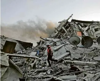  ?? Mohammed Abed/AFP ?? Socorrista anda sobre destroços de prédio bombardead­o por Israel em Gaza