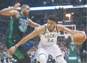  ??  ?? ↑ Giannis Antetokoun­mpo trata de acercarse al aro ante la defensa del dominicano Al Horford, ayer.